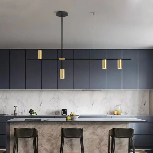 Modern black chandelier pendant lights with gold-toned cylindrical design hang above a kitchen island by DecorBites