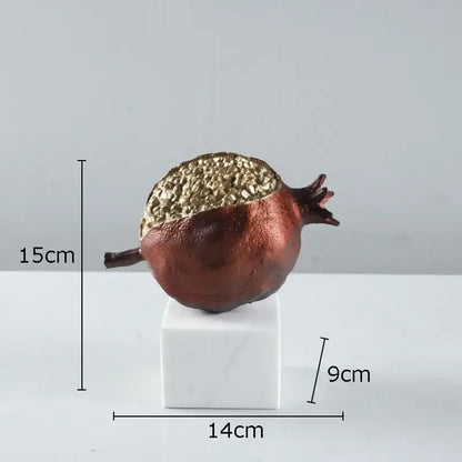 Modern black and gold pomegranate sculpture with textured metallic gold top and matte copper body on white marble base decorbites golden pomegranate