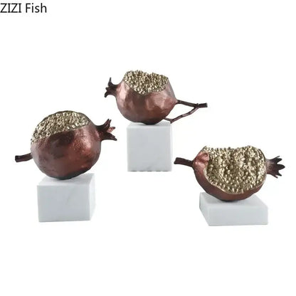 Set of three decorbites golden pomegranate sculptures in copper tone with gold-dusted interiors on white marble bases