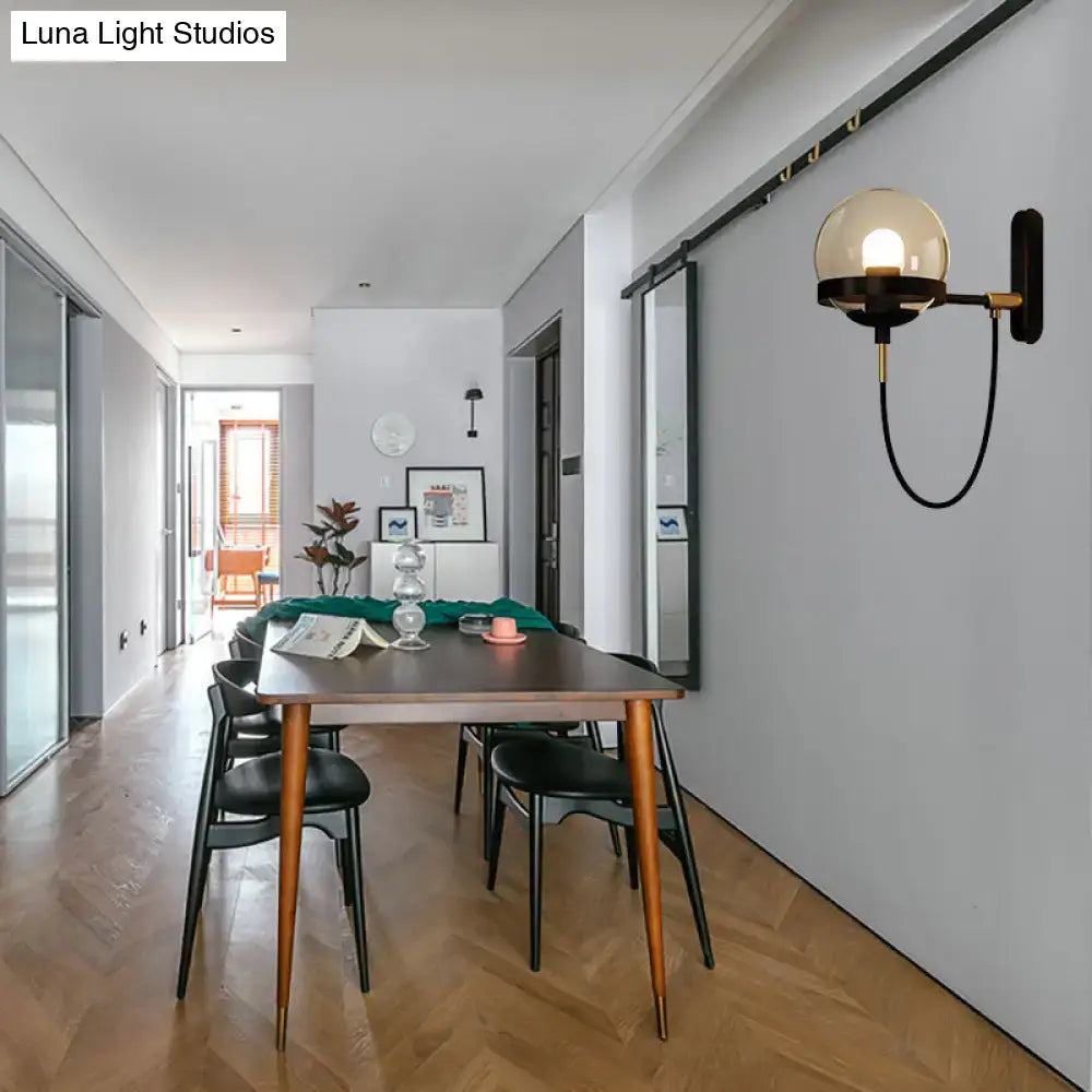 Modern black gold wall lamp with smoke glass spherical globe and black metal arm for living room sconce