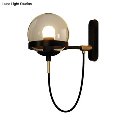 A modern black gold wall lamp featuring a sleek brass frame and a smoke glass globe for living room ambiance