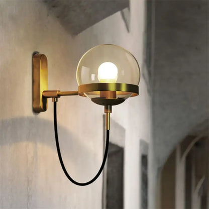 A modern black gold wall lamp with a warm-toned brass sconce and smoke glass globe for living room lighting