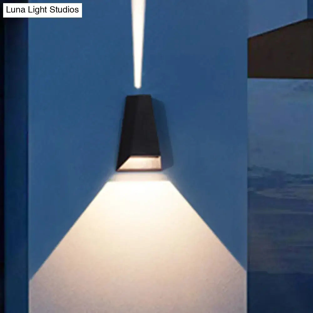 Modern black and gold triangle led wall light casting a focused warm white light for bedroom use