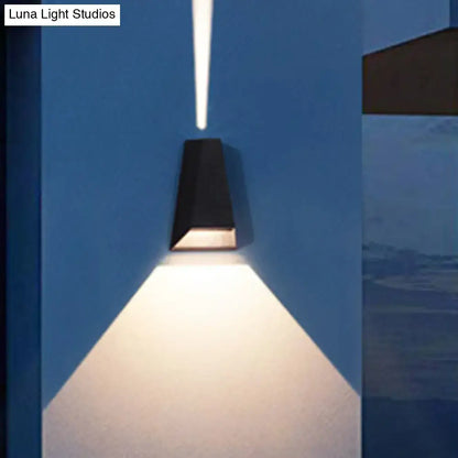 Modern black and gold triangle led wall light casting a focused warm white light for bedroom use