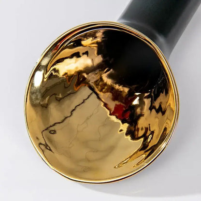 A glossy gold ceramic bowl with a crackled interior and black handle from the decorbites golden trumpet vase set