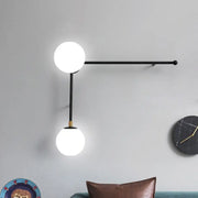 Modern black metal wall lamp with two glowing white glass spheres direct wired electric for bedroom modern design