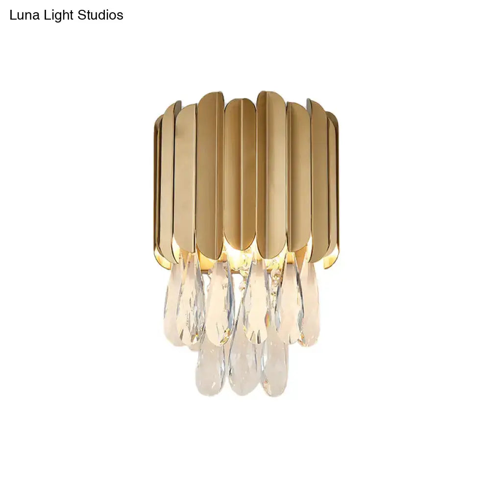 Modern black and gold wall lamp with gold-toned metallic plates and clear crystal teardrop bedroom sconce