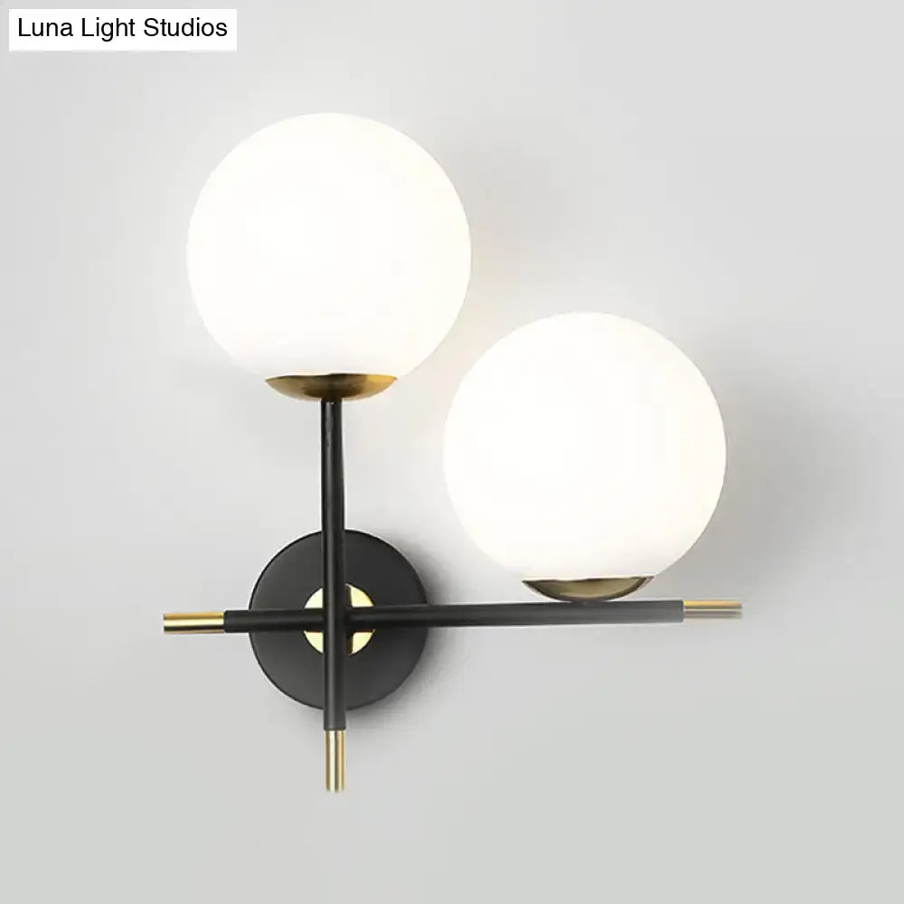 Modern black and brass wall light with two milky glass shades for bedroom lighting