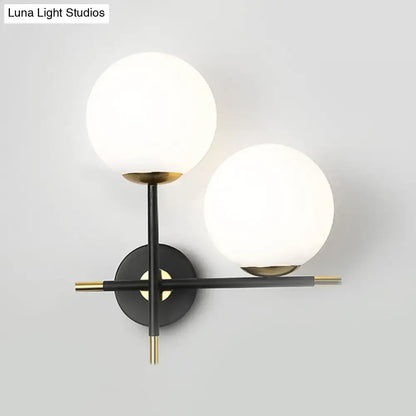 Modern black and brass wall light with two milky glass shades for bedroom lighting