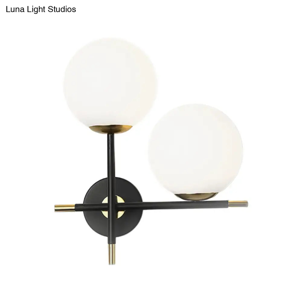 Modern two-light wall light with milky glass shade black metal frame and gold accents for bedroom lighting