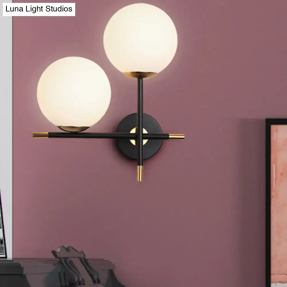Modern black and gold wall light with two milky glass shades and black metal frame for bedroom use