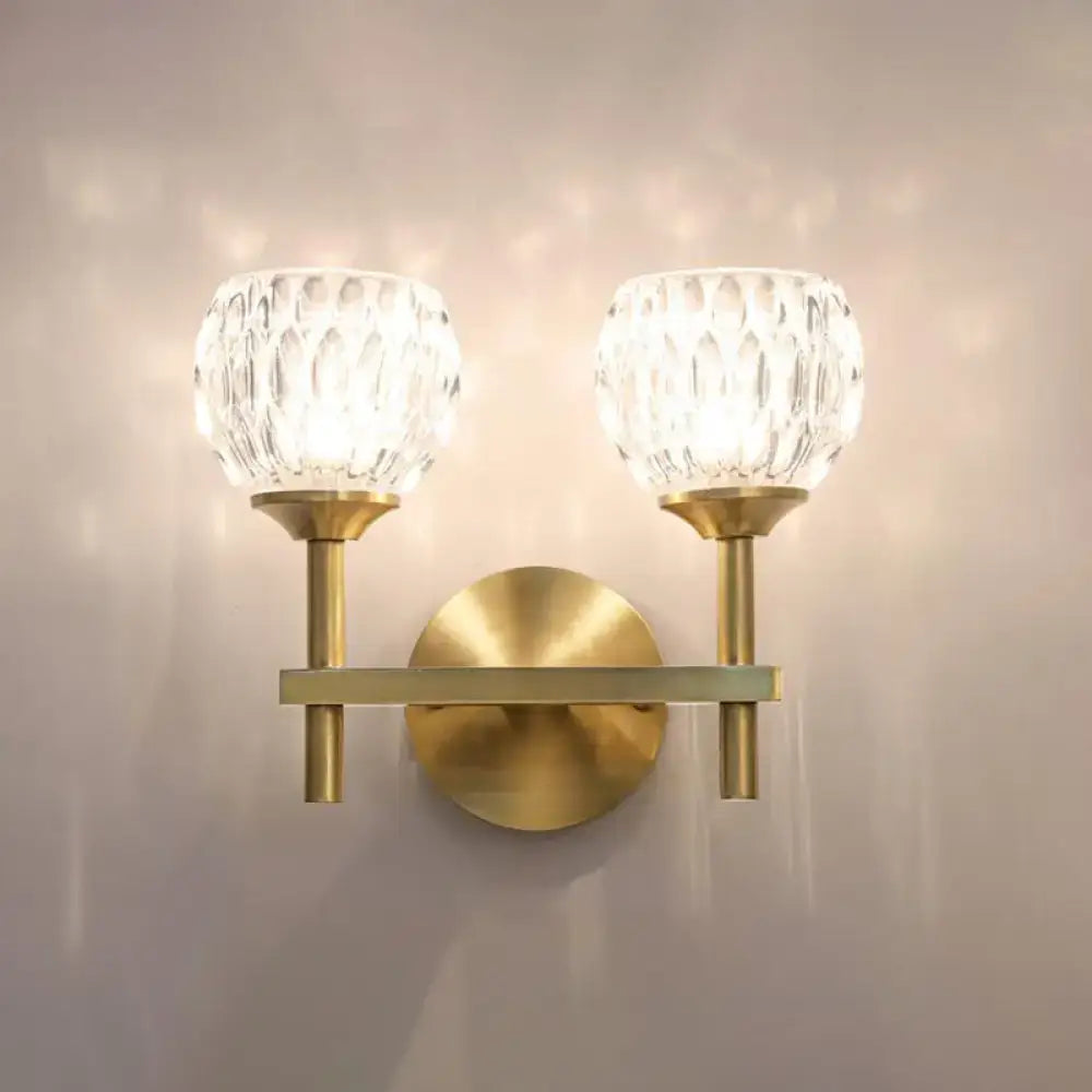 Brass-finished wall light with two faceted crystal dimpled glass shades for living room illumination