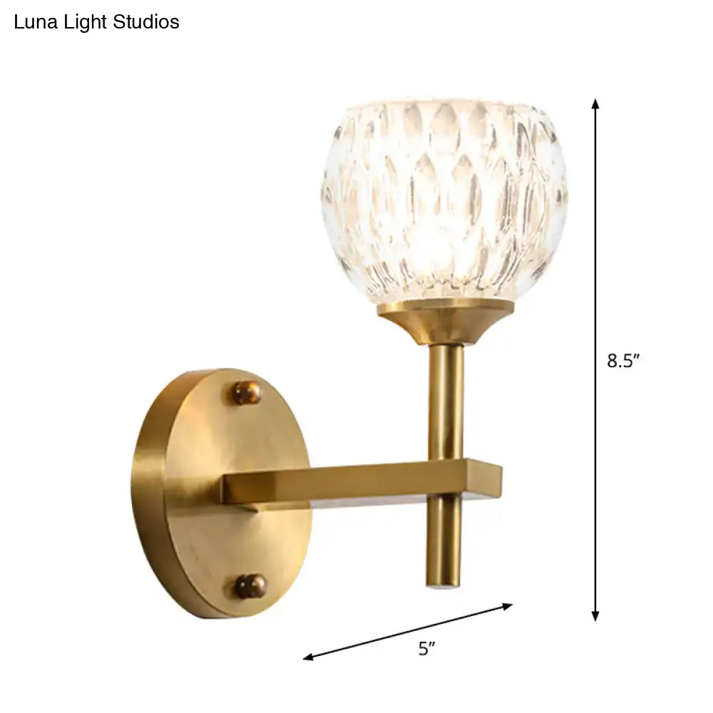 Brass-finished wall light with faceted crystal glass shade featuring dimpled glass for living room use
