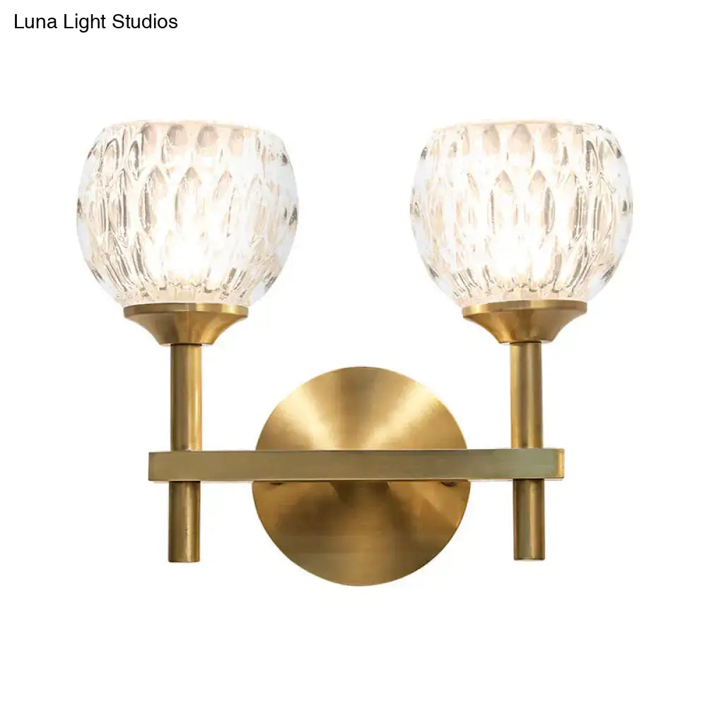 Brass-finished wall light with two textured crystal glass shades featuring dimpled glass for living room use