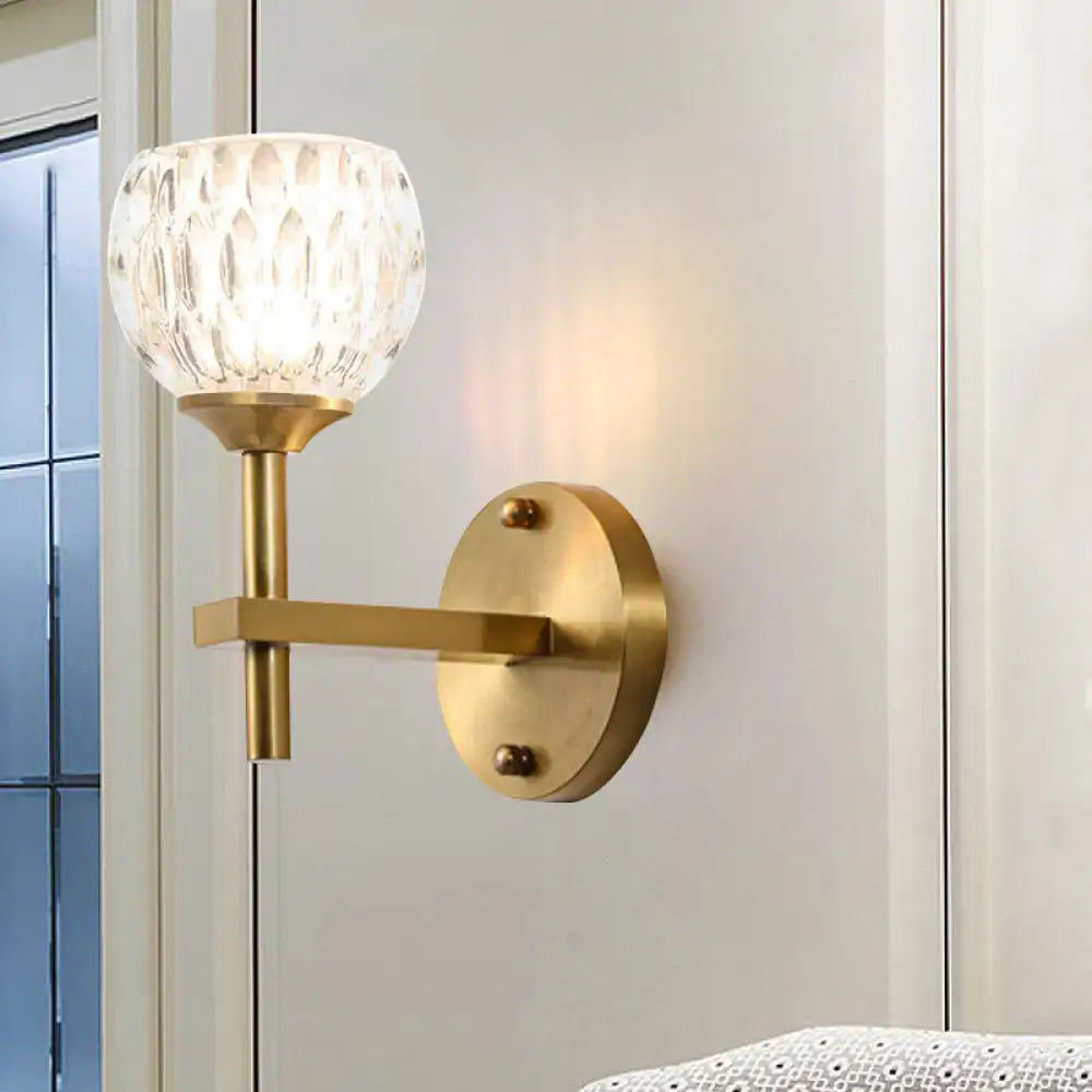 Gold-toned modern wall light with dimpled clear glass shade for living room illumination and elegant decor