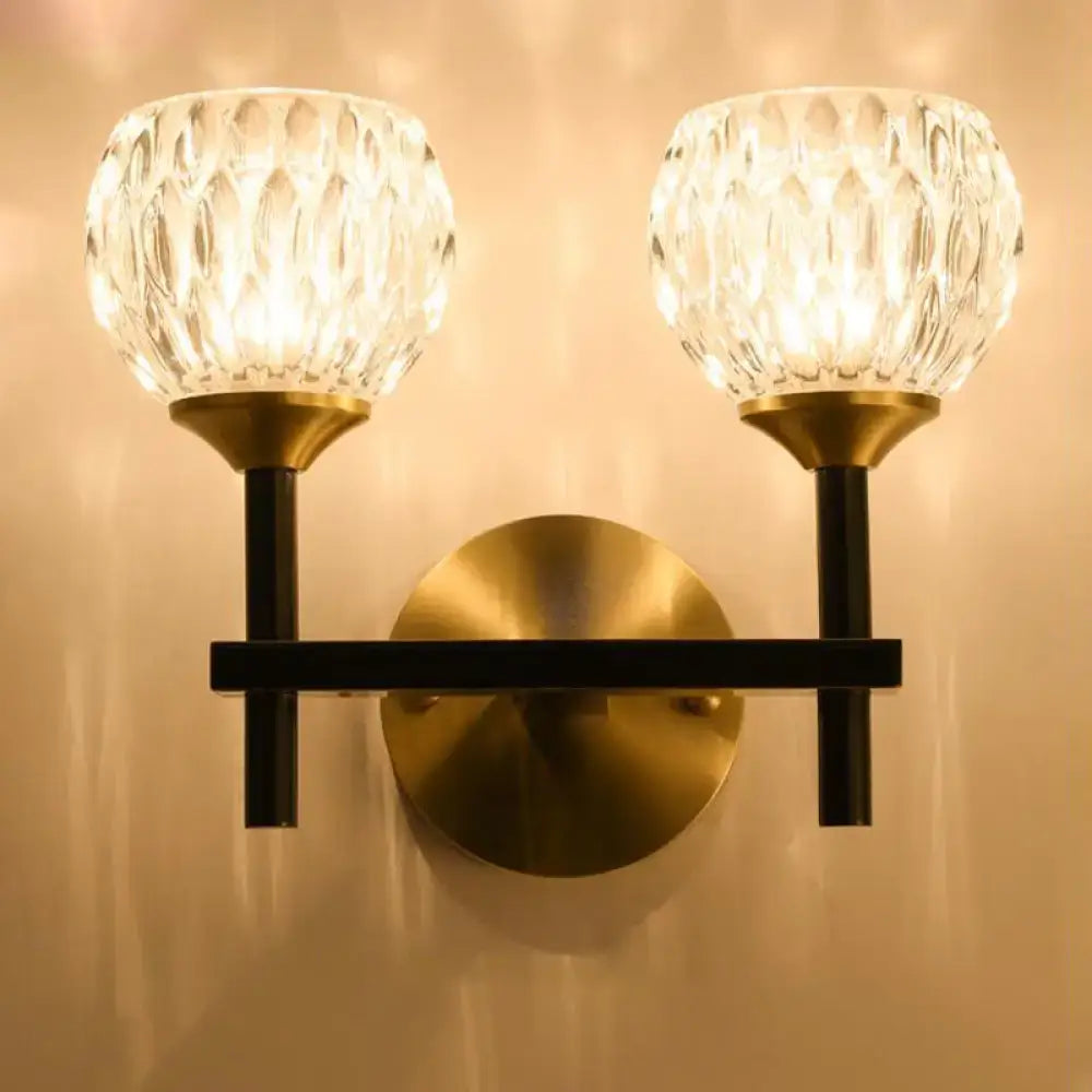 Brass-finished wall light with two faceted crystal globe shades and dimpled glass for living room lighting