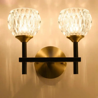 Brass-finished wall light with two faceted crystal globe shades and dimpled glass for living room lighting