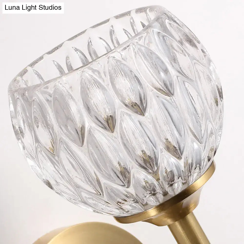 Modern black and gold wall light with a brass base and clear leaf-patterned dimpled glass for living room use
