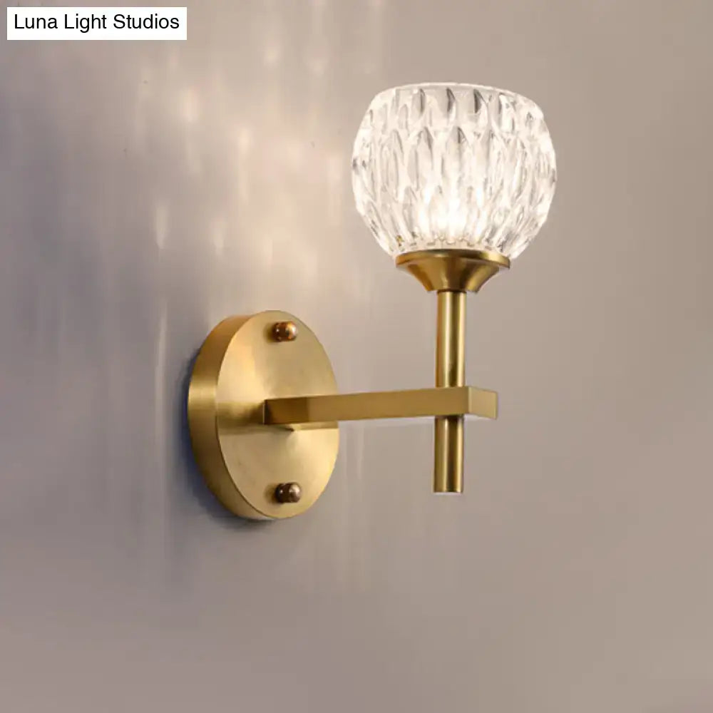 A brass-finished wall light with faceted dimpled glass shade for stylish living room lighting
