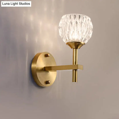 A brass-finished wall light with faceted dimpled glass shade for stylish living room lighting