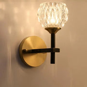 Brass-finished wall light with dimpled crystal glass shade and black metal arm for living room use
