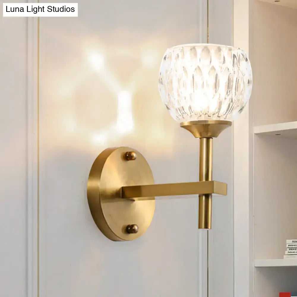 Modern black and gold wall light with brass finish and faceted dimpled glass shade for living room lighting
