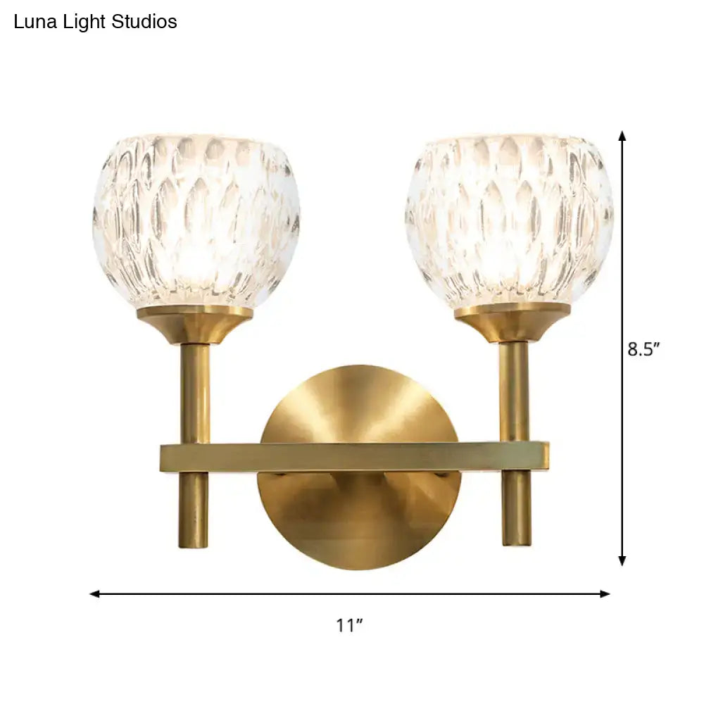 Brass-finished wall light with two textured crystal glass shades featuring dimpled glass for living room use
