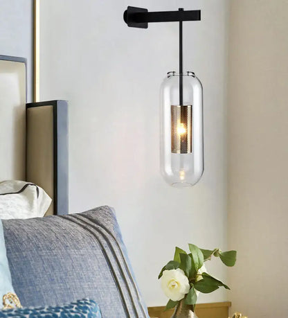 Modern black and gold wall mounted light with clear glass cylinder and textured gold-toned inner sleeve for living room