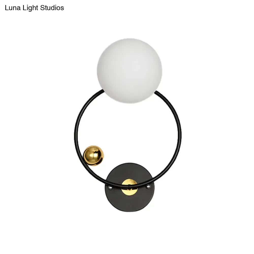 Modern black and gold wall sconce light with opal glass shade featuring matte white spherical glass and polished gold accents