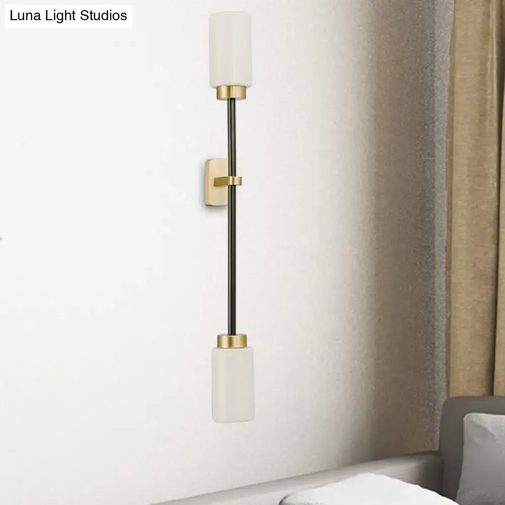 Modern black and gold wall sconce with sleek metal rod and white glass shade for living room lighting