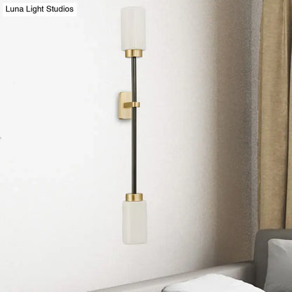Modern black and gold wall sconce with sleek metal rod and white glass shade for living room lighting