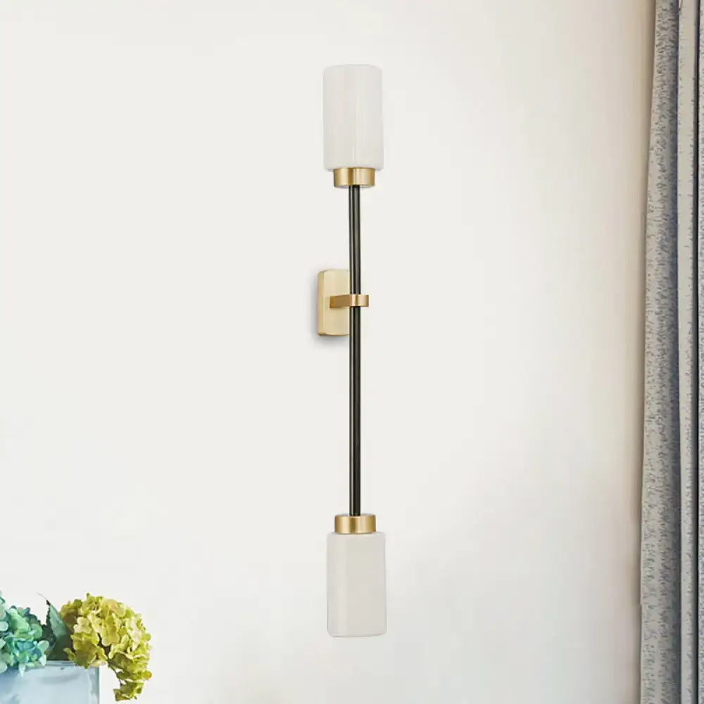 Modern black and gold wall sconce with white glass shade and frosted cylindrical glass for living room lighting