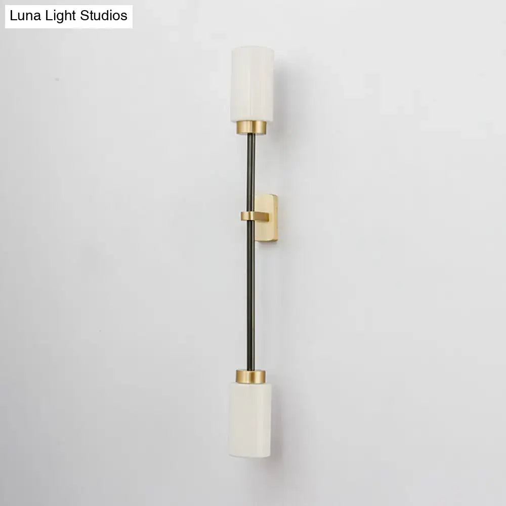 Modern black and gold wall sconce featuring white glass shade for living room with sleek metal rod and frosted glass cylinders