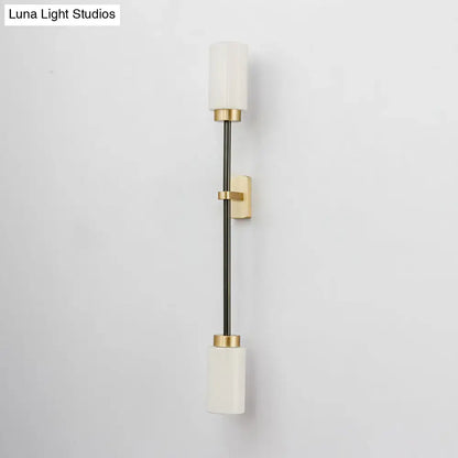 Modern black and gold wall sconce featuring white glass shade for living room with sleek metal rod and frosted glass cylinders