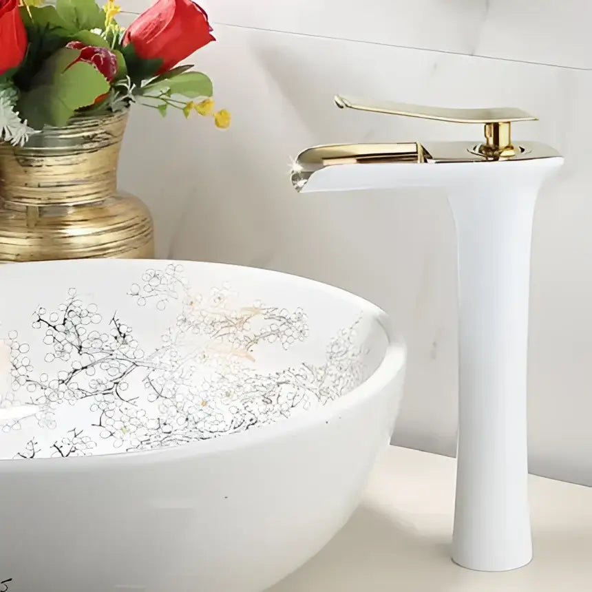 White ceramic bowl sink with silver floral pattern paired with decorbites gold waterfall basin faucet for bathroom use