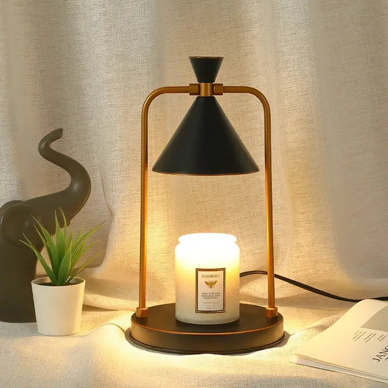 A sleek black and gold decorbites candle warmer lamp with a conical shade holding an illuminated white scented candle