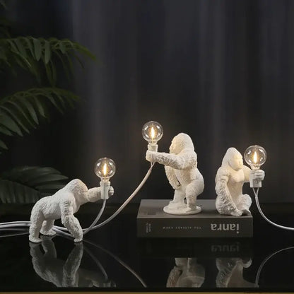 Modern black resin gorilla night light set with three white figurines holding lit Edison bulbs for decorbites gorilla night use