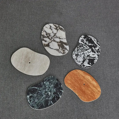 Five irregular flat stone coasters with natural marble and wood patterns complementing decorbites green marble wall sconce