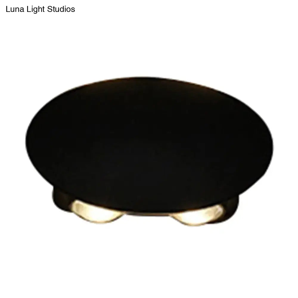 Modern black hexagonal wall washer sconce with two warm-toned led bulbs embedded in oval ceiling light base
