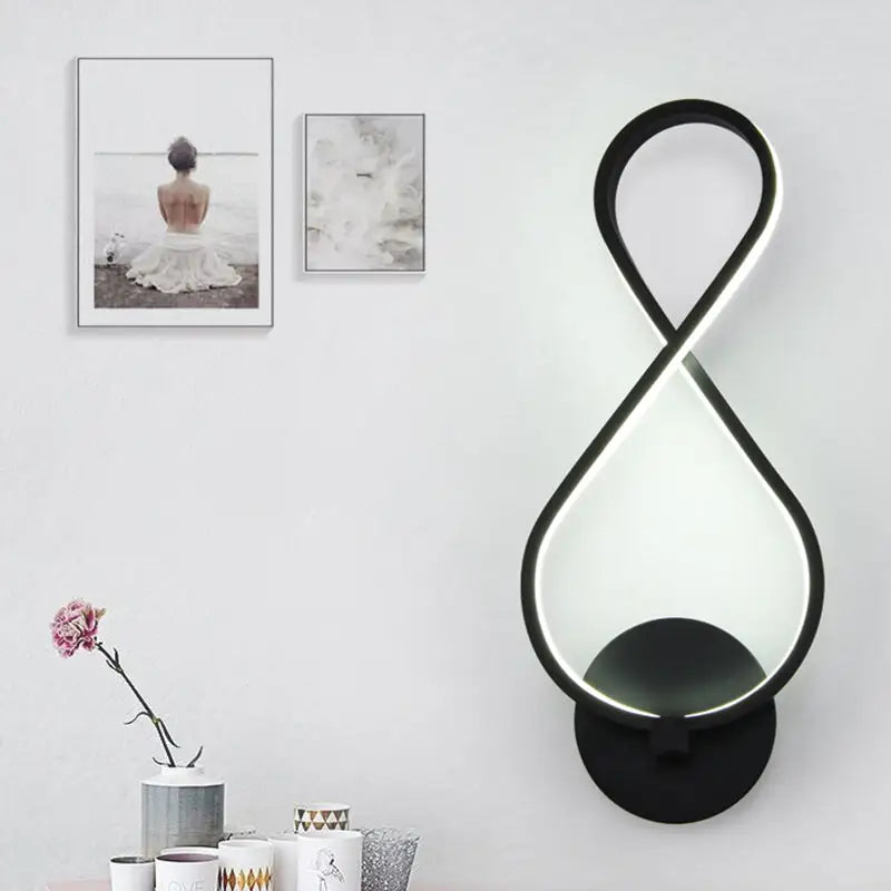 Modern black infinity led sconce light fixture with glowing white light strip along curved edges for bedroom wall lighting