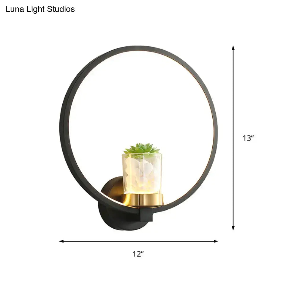 Modern black led light circular wall sconce with metal frame, gold base, and clear vase holding a green succulent for bedroom