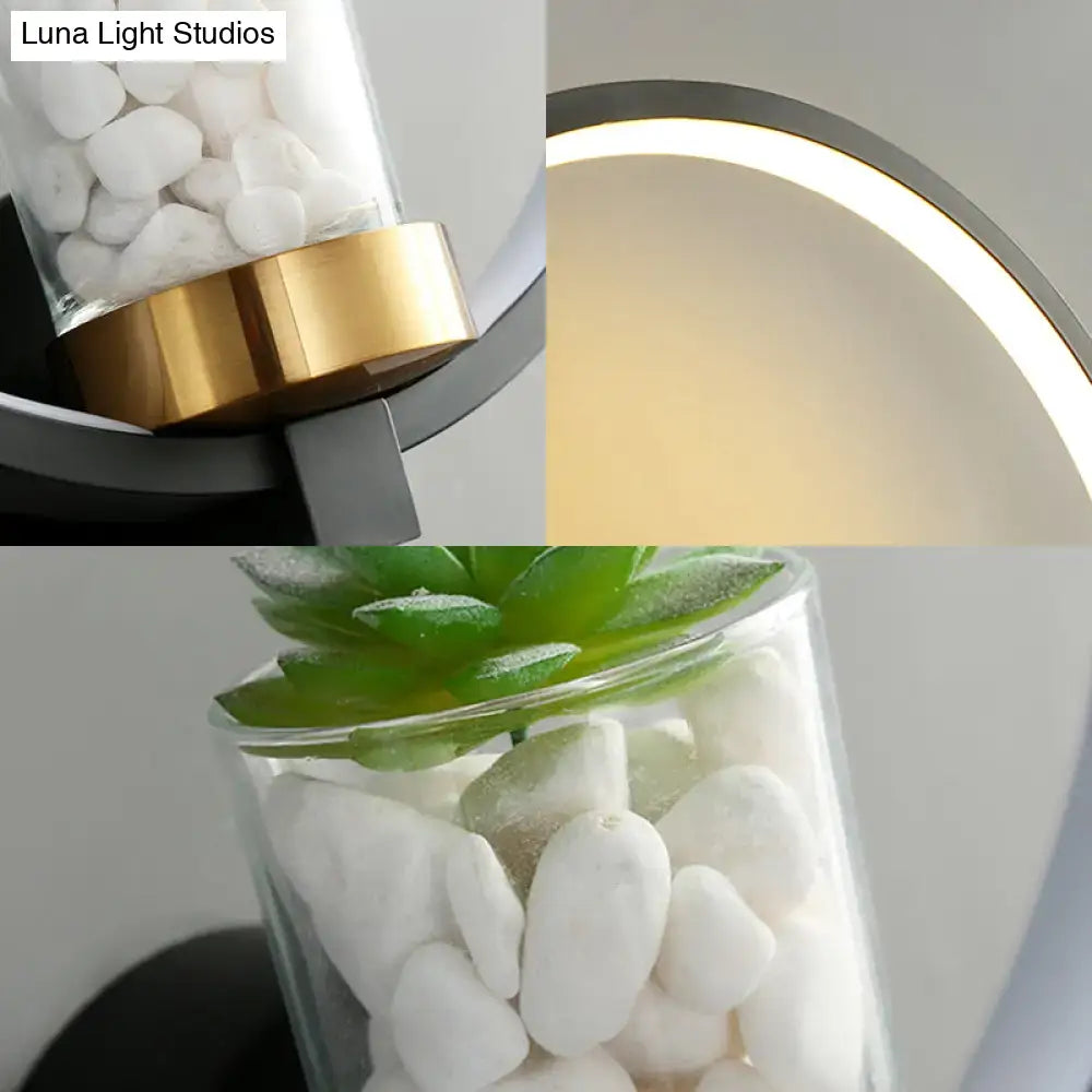 Modern black led light wall sconce with sleek table lamp featuring gold accent ring and glass shade filled with white pebbles