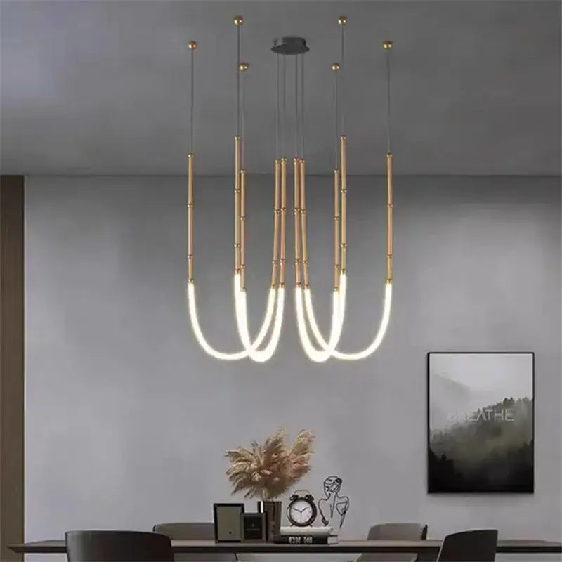 Modern gold-toned pendant chandelier with sleek curved illuminated arms for dining room by decorbites leda black line