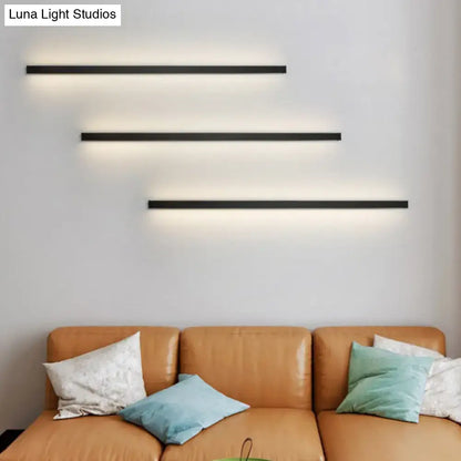 Three sleek black linear flush mount wall sconces with warm ambient lighting for modern hallway use