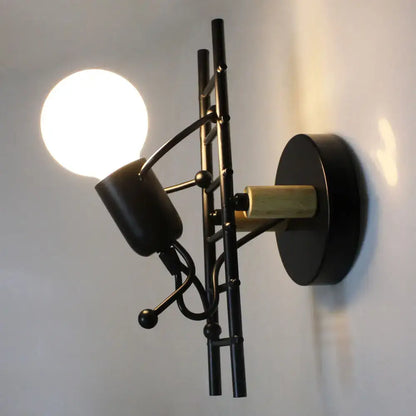 Modern black little man led wall light featuring a black metal sconce with brass accent and adjustable spotlight