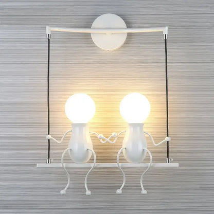 Modern black little man led wall light with two whimsical figure-shaped bulbs holding hands mounted on white wall