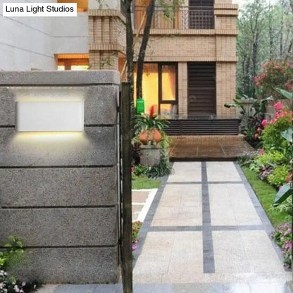 Modern black luna outdoor wall light with sleek white panel and warm led glow mounted on textured gray stone pillar