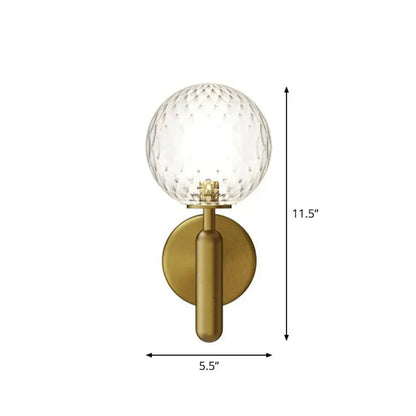 Brass-finished black gold wall sconce with clear faceted glass globe for modern stairs lighting