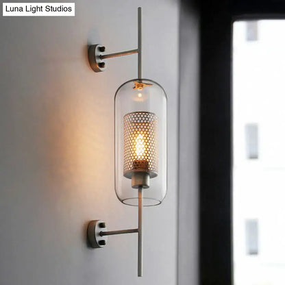 Modern black mesh wall mount lamp with clear glass cylinder and amber filament bulb on slender metallic arms