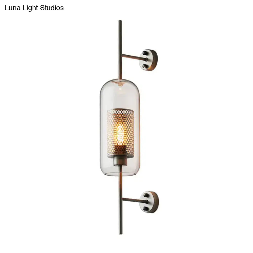 Modern black mesh wall mount lamp with a clear glass cylinder and amber honeycomb metal shade with brass hardware